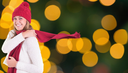 Happy blonde in winter clothes against blurry yellow christmas light circles