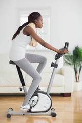 Fototapeta premium Side view of a black woman doing exercise bike