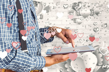 Geeky businessman using his tablet pc against grey valentines heart pattern