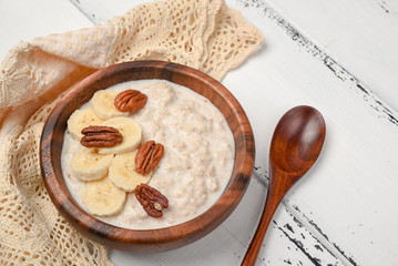 Oatmeal porridge with banana and pecan nuts for breakfast