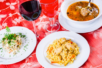 Three plates with lunch dishes on table. Salad, soup with meatballs and pilaf. Armenian food