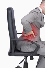 Side view of business man with backache sitting in an office chair over white background