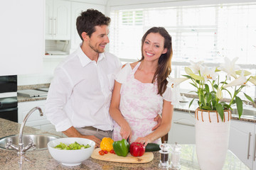 Obraz na płótnie Canvas Portrait of happy couple cutting vegetables in kitchen