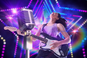Fototapeta na wymiar Pretty girl playing guitar against digitally generated star laser background
