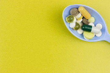 Capsules and tablets on plastic spoon. Medicine pharmaceutical theme. Empty space for text