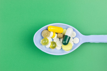 Capsules and tablets on plastic spoon. Medicine pharmaceutical theme. Free space for text