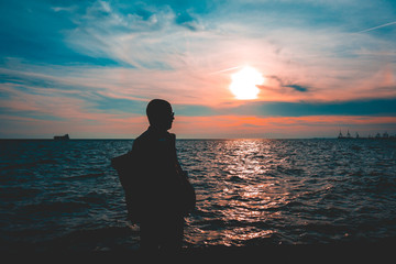 Silhouetted man on a seafront promenade at dusk