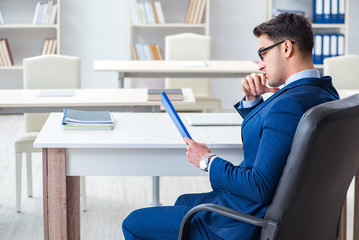 Young handsome businessman employee working in office at desk