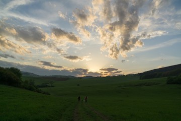Obraz na płótnie Canvas People walking on a meadow during sunset. Slovakia