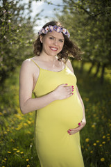 Fototapeta na wymiar Beautiful pregnant woman relaxing outside in the orchard