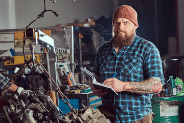 Two bearded mechanics specialist repairs the car engine which is raised on the hydraulic lift in the garage.