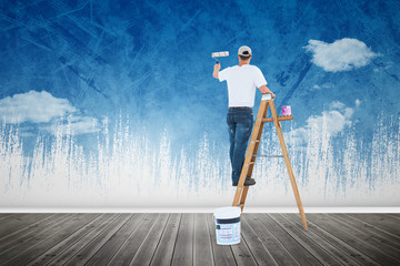 Man on ladder painting with roller against painted sky