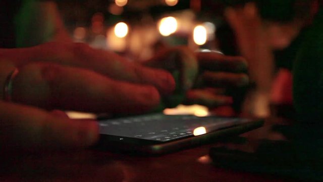 Sound engineer mixing at musical performance in night club; close-up at hands and digital tablet