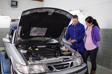 Mechanic showing a clipboard to a woman