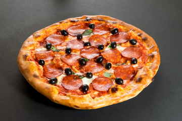 Pizza with pepperoni sausage and olives side view