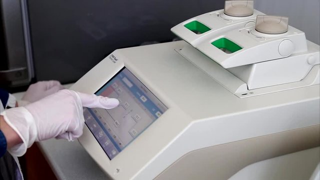 Scientist with gloved hand is programming DNA analysis in real-time PCR-cycler.