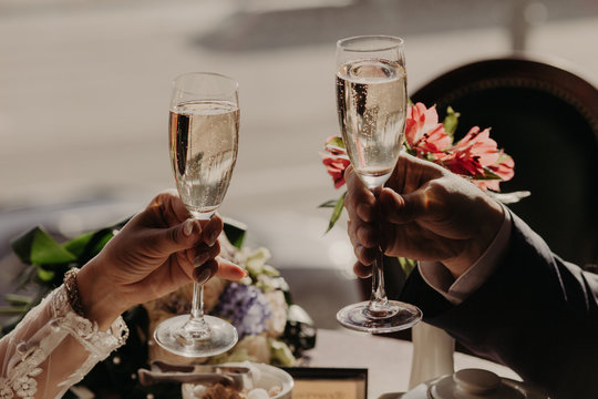Close up image of glasses of champagne or wine, clink glasses, celebrate together their wedding day, hve festive event. People, dating and celebration concept