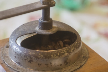 An old wooden hand coffee grinder with rusty crank