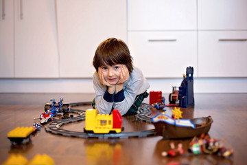 Child boy playing in living room with a toy train