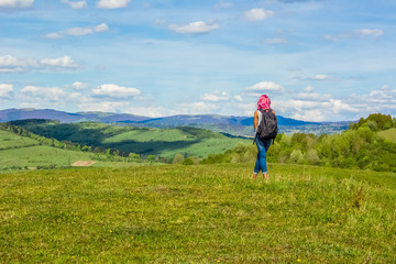 travel backpack informal girl with pink hair back to camera walk on beautiful nature forest mountain landscape background 