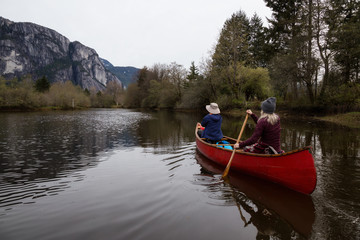Couple adventurous friends canoeing on the lake with Chief Mountain in the background. Taken in Squamish North of Vancouver, British Columbia, Canada.