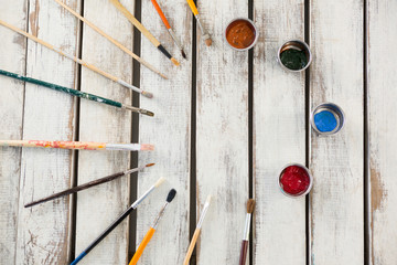 Paintbrushes and watercolors arranged on wooden surface
