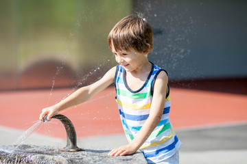 Sweet child, boy, splashing water from a fountain