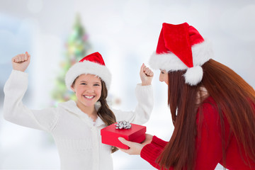 Mother and daughter with gift against blurry christmas tree in room