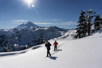 Naklejka na ściany i meble Adventurous man and woman are snowshoeing in the snow. Taken in Artist Point, Northeast of Seattle, Washington, United States of America.