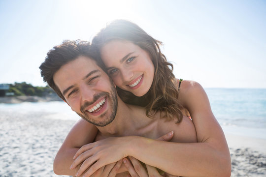 Portrait of happy shirtless couple embracing at beach