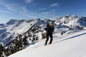 Naklejka na ściany i meble Adventurous woman is snowshoeing in the beautiful mountainous landscape. Taken in Artist Point, Northeast of Seattle, Washington, United States of America.
