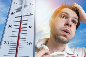 Hot weather concept. Young man is sweating. Thermometer is showing high temperature. Sun in...
