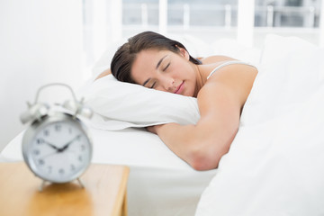 Obraz na płótnie Canvas Sleeping woman with blurred alarm clock on bedside table