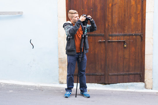 Young photographer with a monopod making photos in city