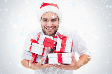 Handsome festive man holding gifts against snow falling