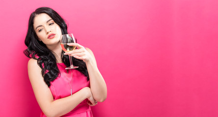 Young woman drinking wine on a solid pink background