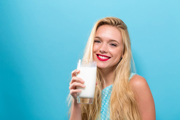 Happy young woman drinking a glass of milk on a solid background