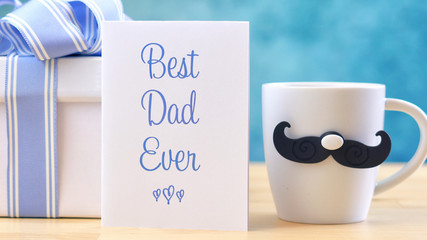 Happy Father's Day close up of Best Dad Ever greeting card and coffee mug on table.