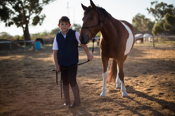 Boy holding the reins of a horse in the ranch