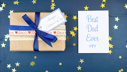 Happy Father's Day overhead with gift and Best Dad Ever card on dark wood table.
