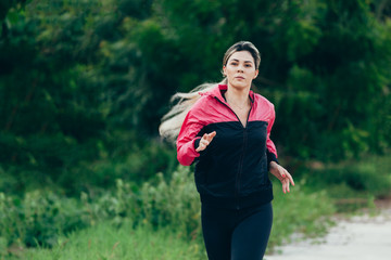 Running woman. Female runner jogging during outdoor workout. Fitness model outdoors.