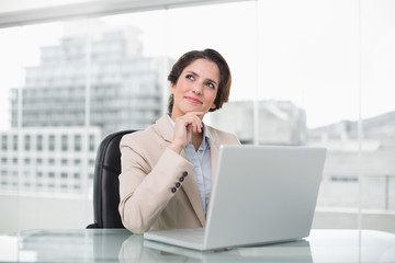 Fototapeta premium Thoughtful businesswoman using laptop at her desk
