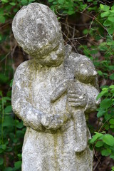 Old sculpture of a boy with his teddy bear in his hand on a tomb of the cemetery of Berlin-Charlottenburg