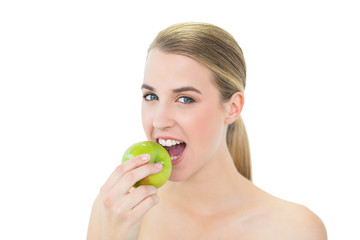 Smiling attractive blonde eating green apple
