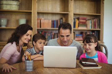 Fototapeta na wymiar Parents and kids using laptop on table in study room