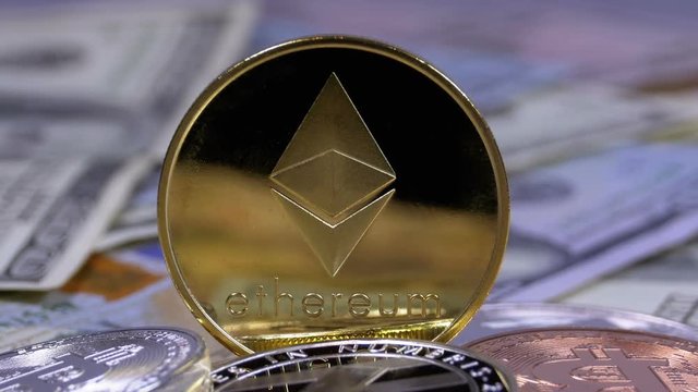 Gold Ethereum Coin, ETH and Bills of Dollars are Rotating. Different Crypto Currency Close-up. Macro. Dollar banknotes of various denominations on which lies the cryptocurrency.