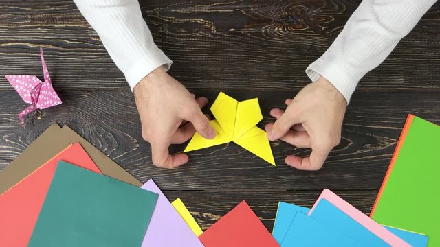 Man made origami butterfly, top view. Origami figures, colorful paper and male hands. How to make an easy origami butterfly.