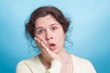shocked young woman, isolated against blue studio background