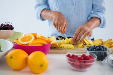 Mid-section of woman cutting fruits on chopping board