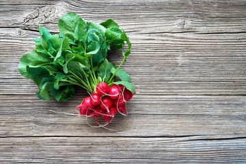 Organic food. Bunch of red radish on rustic wooden background. Top view, copy space. Healthy food